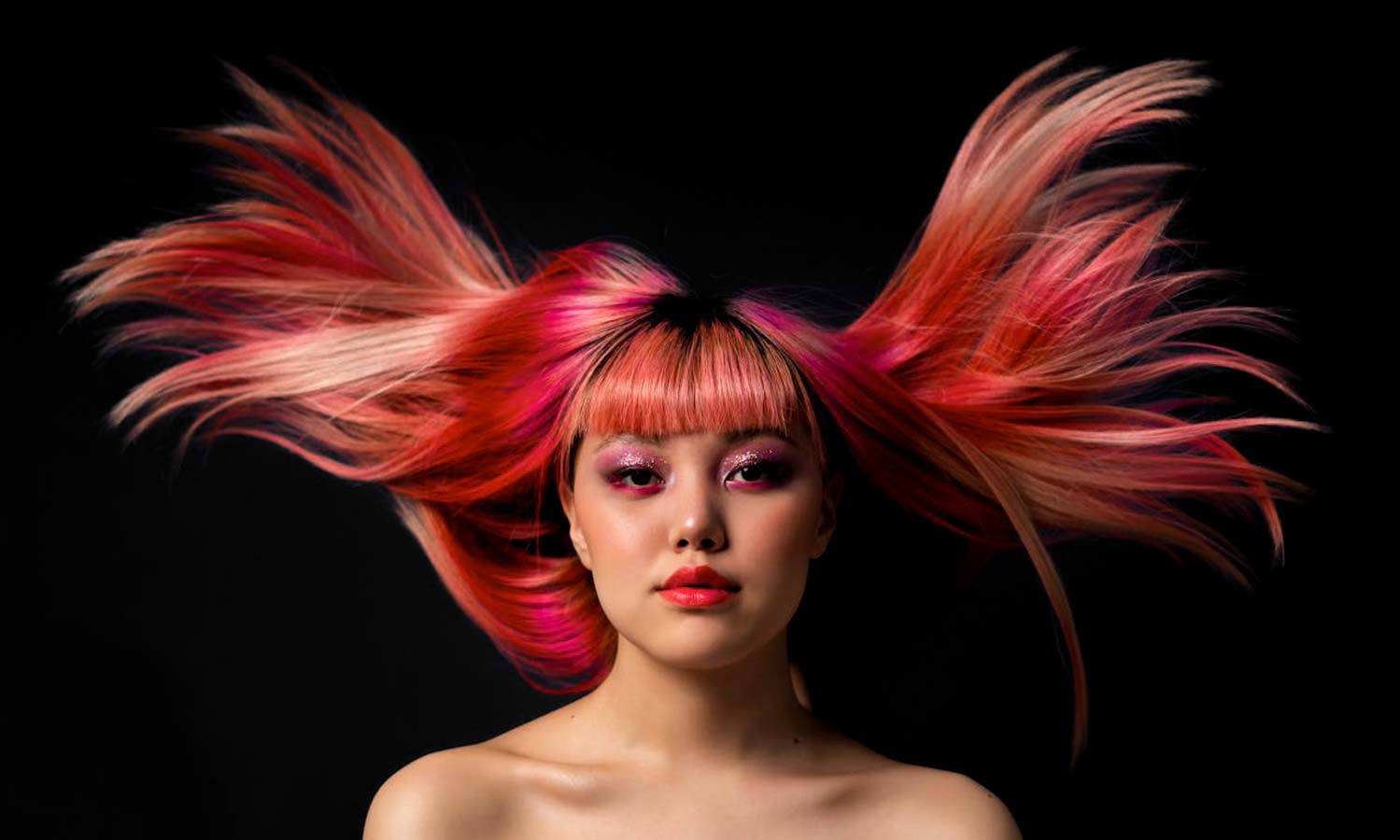Ritratto con capelli rosa e rossi su fondo nero, immagine di campagna